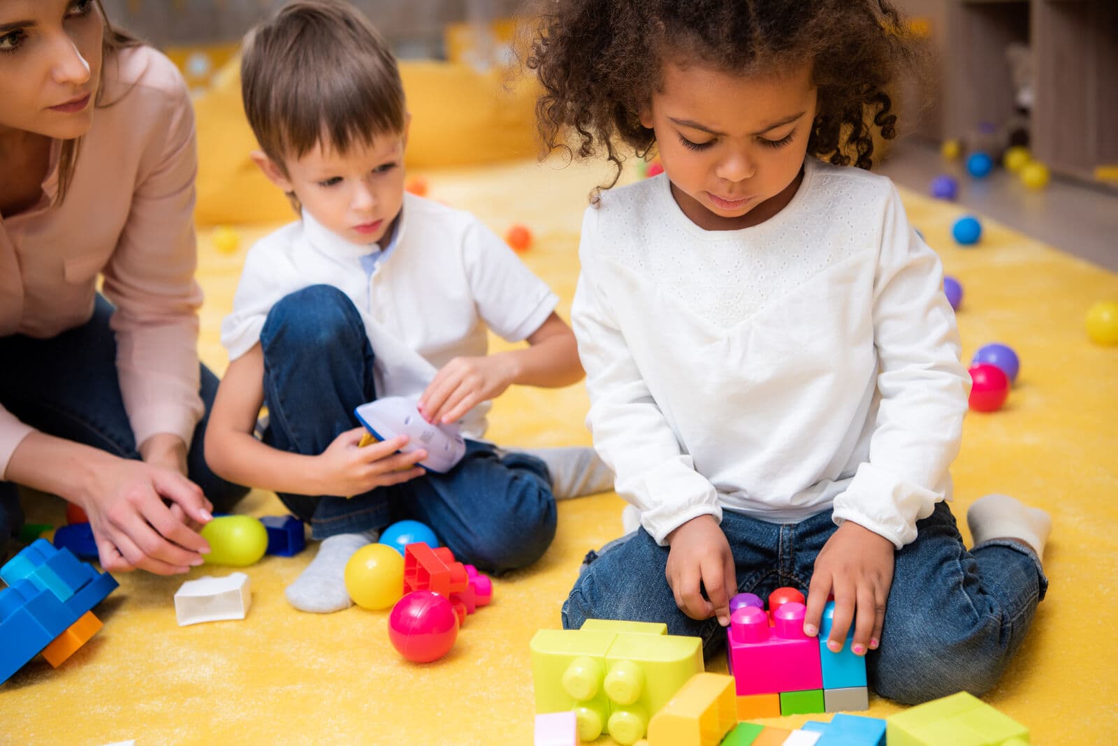 Niños construyendo bloques con una maestra