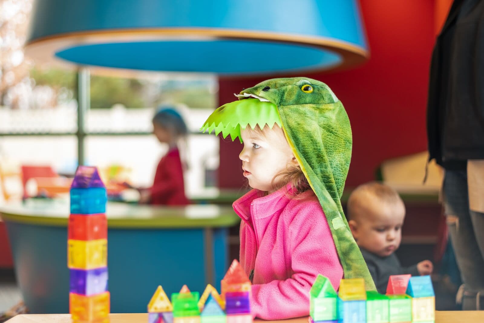 Un niño con capucha de dinosaurio jugando con bloques