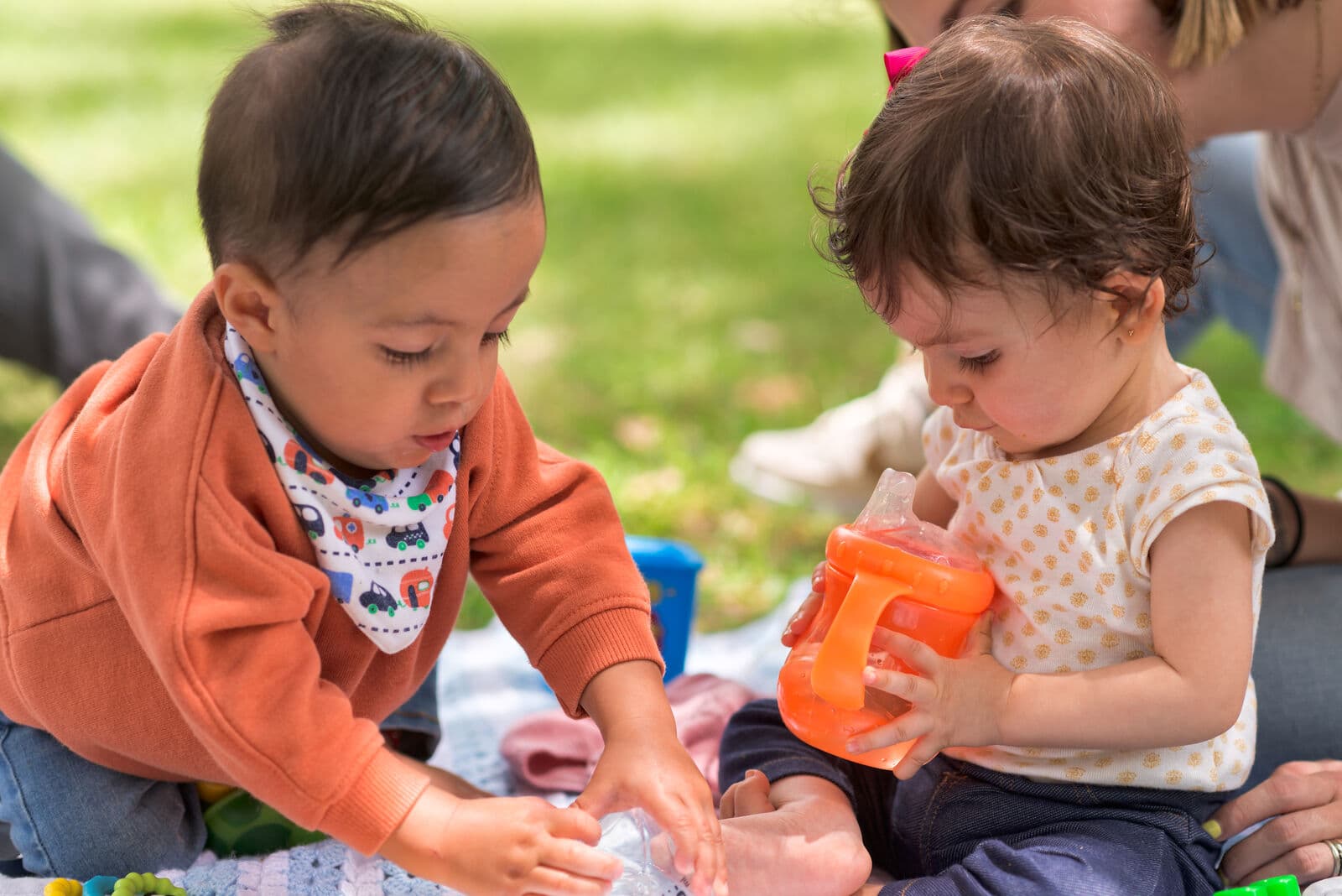 Toddlers playing outdoors on a blanket in the sunlight